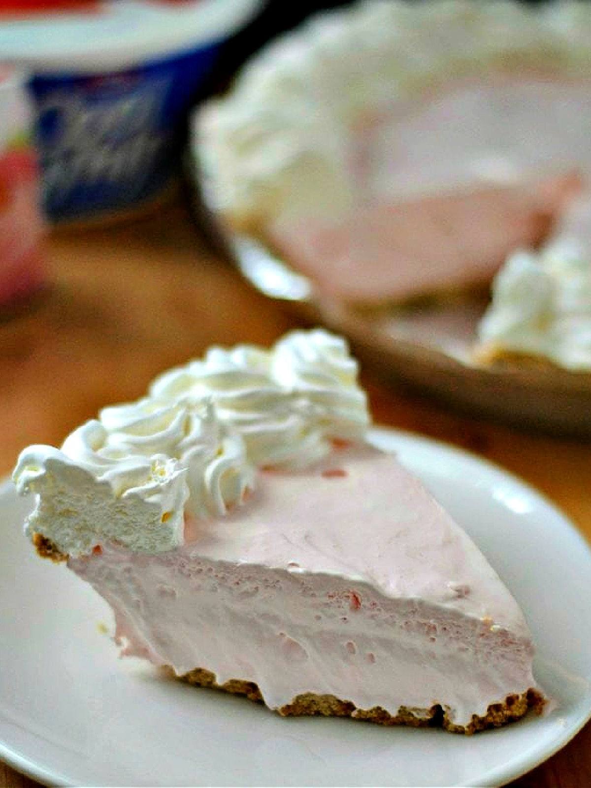 Strawberry Cream Cheese Pie Slice of strawberry pie topped with whipped cream on a plate.
