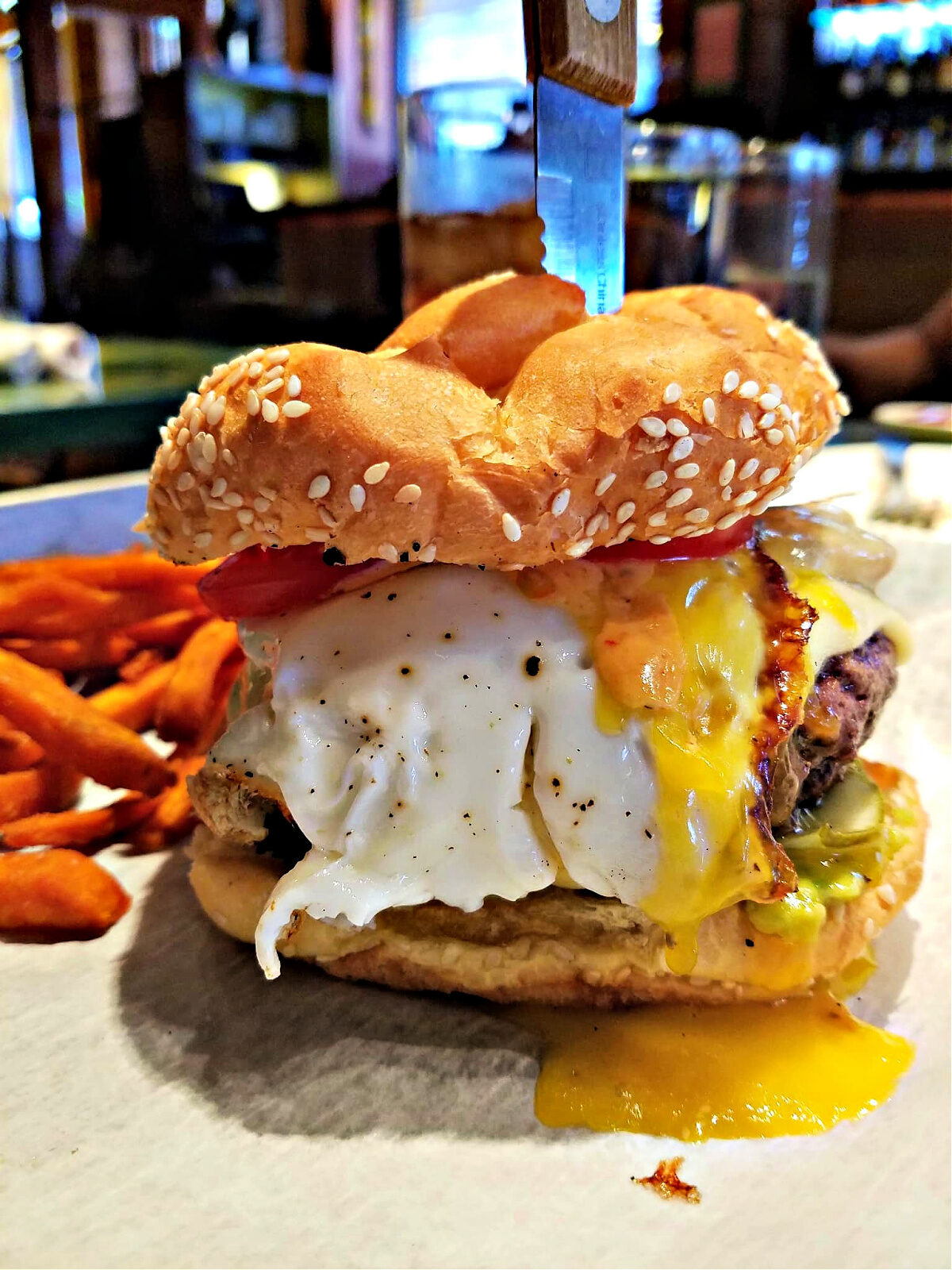 Where To Eat in Pittsburgh Hamburger with runny egg and a knife stuck in it served with sweet potato French fries.