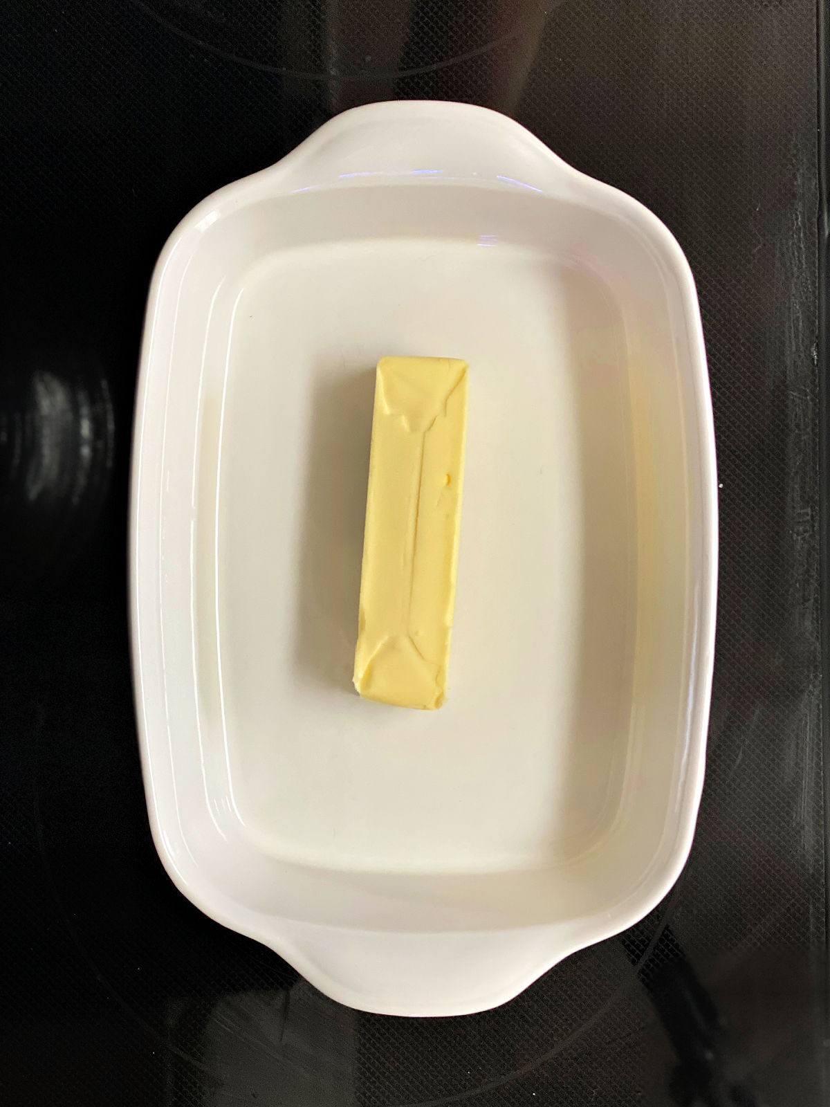 Stick of butter in a white baking dish.
