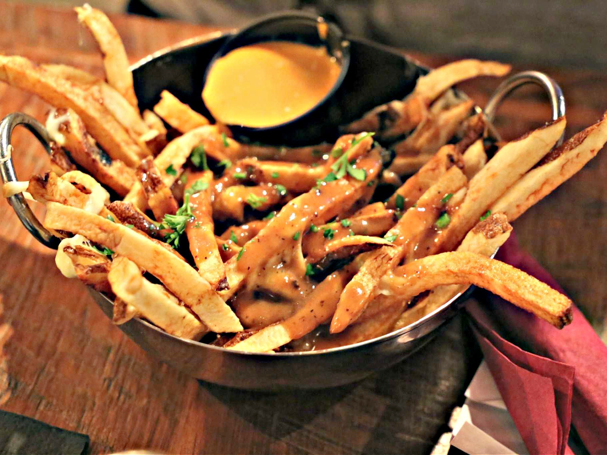 Where To Eat in Pittsburgh A bowl of poutine with a side of cheese sauce.