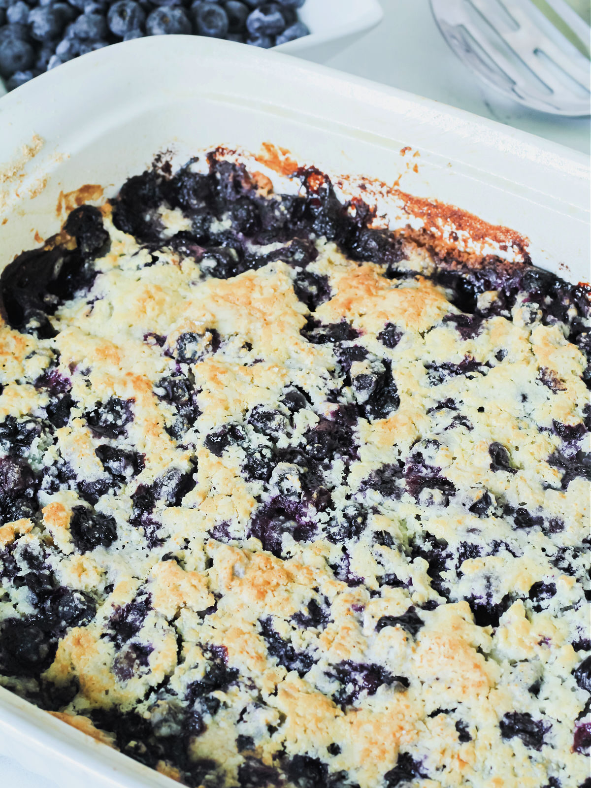 Baked blueberry cobbler in a white baking dish.