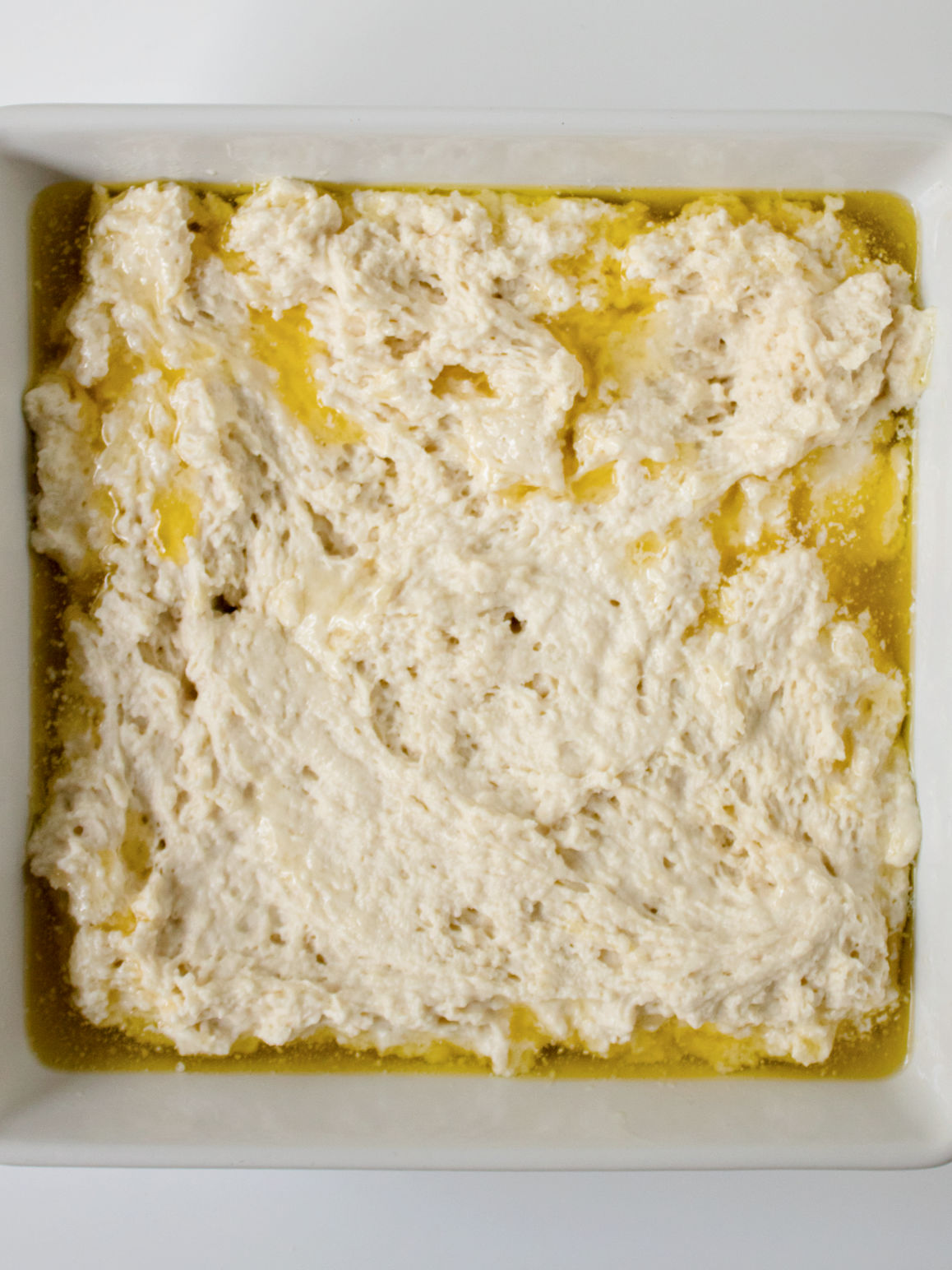 Unbaked biscuit dough in a white ceramic baking dish.