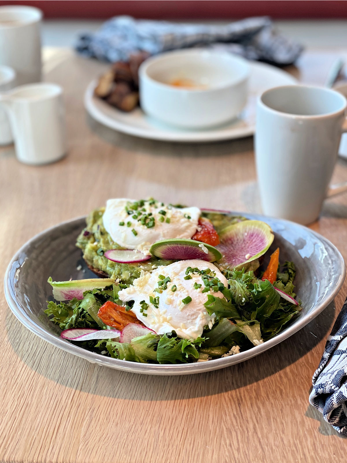Avocado toast made with smashed avocado, roasted tomato, two poached eggs, local field greens.