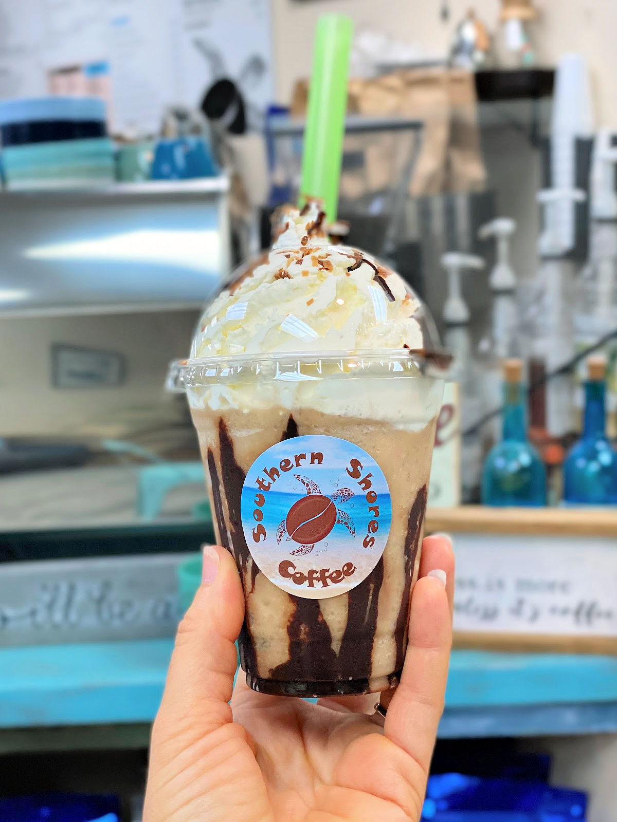 Bushwacker frozen frappe with whipped cream and a green straw.