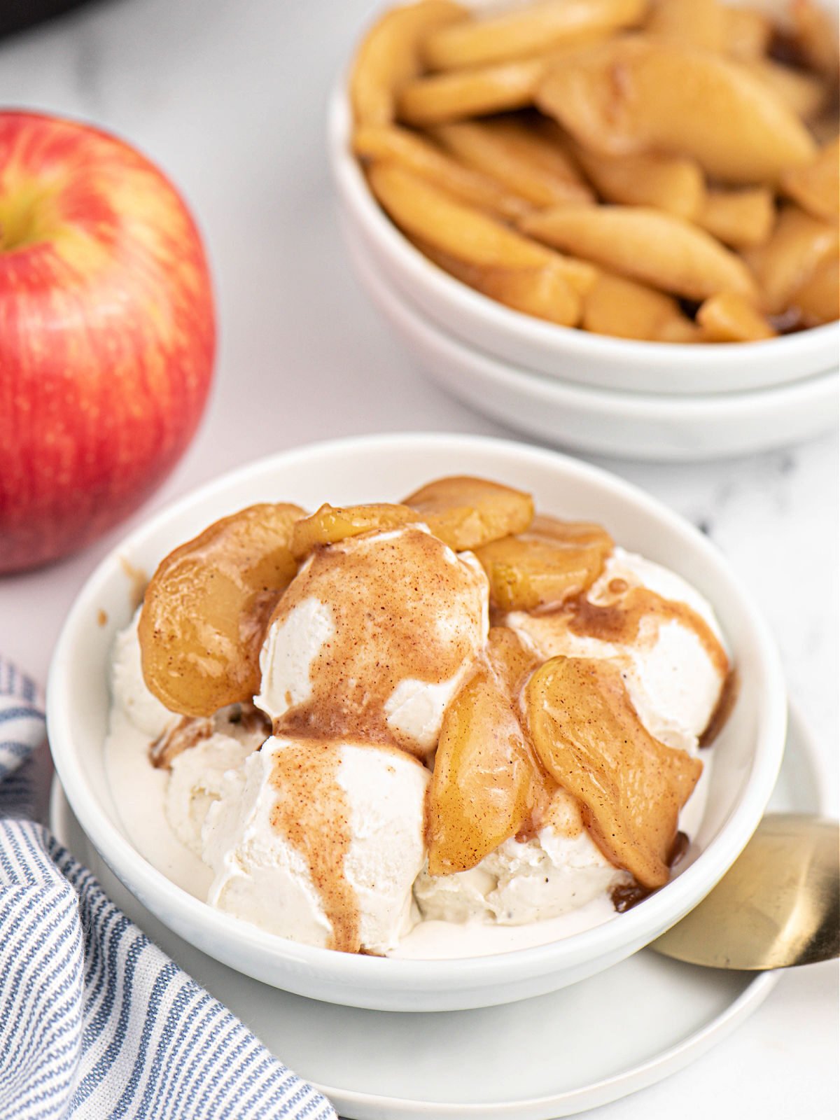 Vanilla ice cream with fried apples in a white bowl.