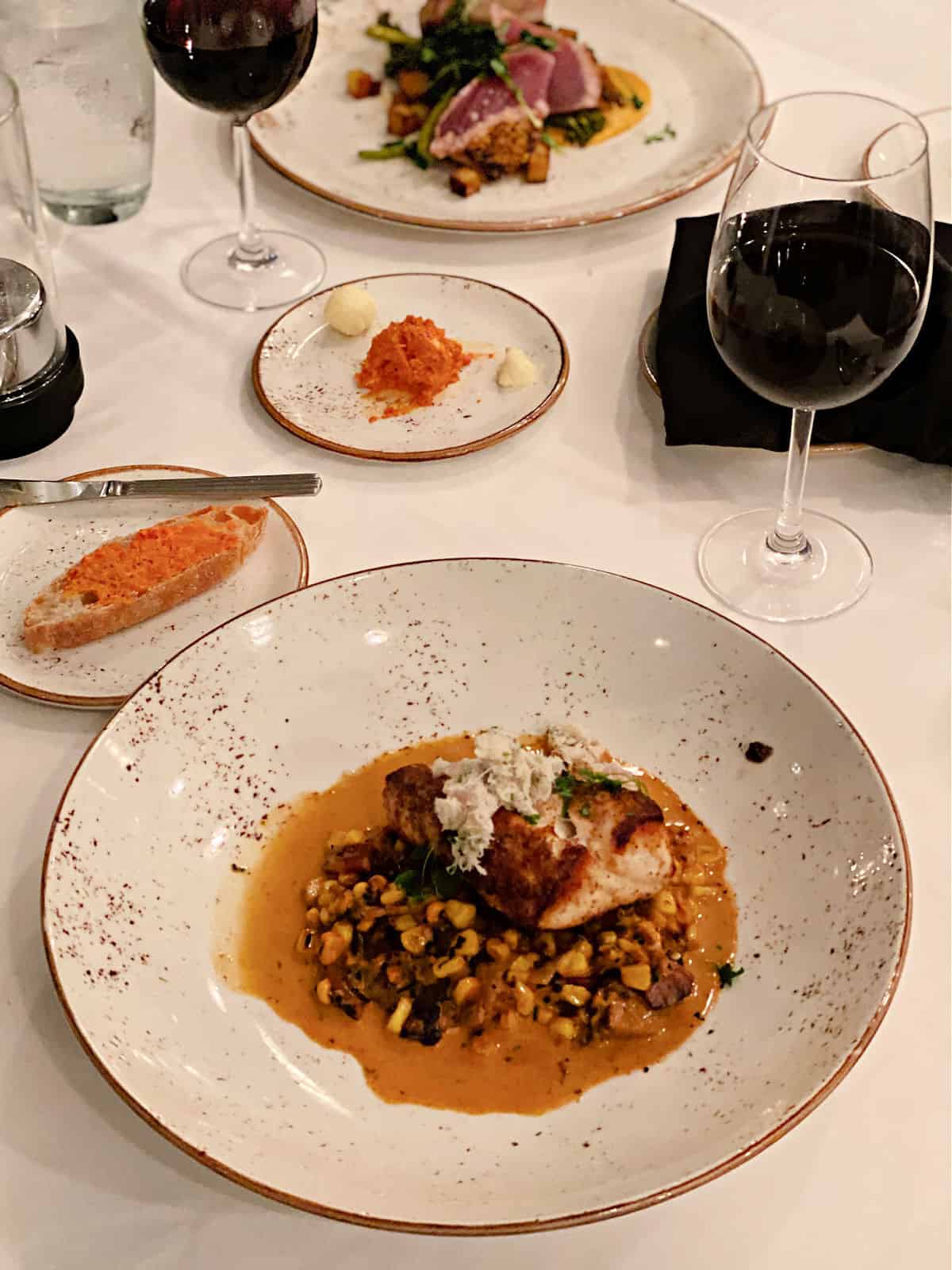 Seared Gulf grouper over pork belly creamed corn, topped with Alabama crab salad and served with red wine at Voyagers in Orange Beach.