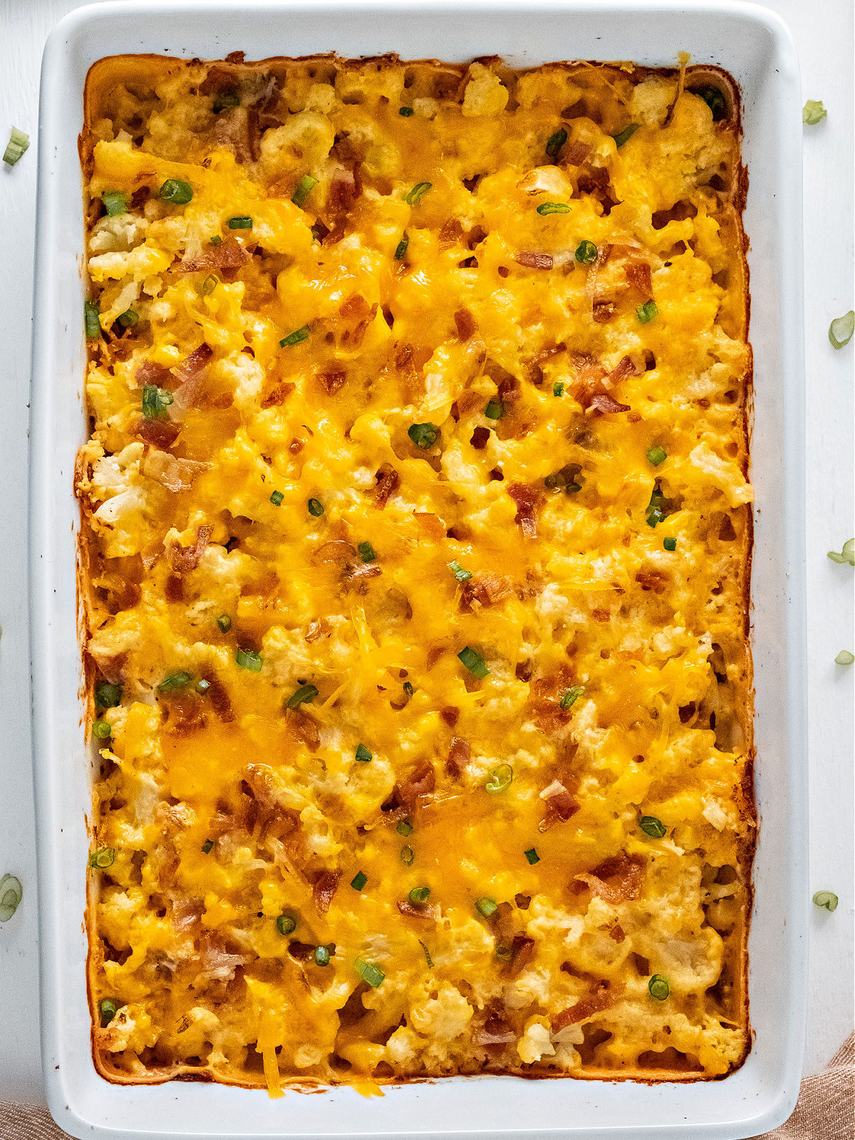 White baking dish filled with baked cauliflower casserole.