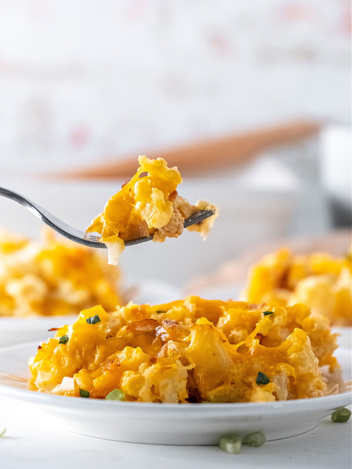 Fork holding a bite of cauliflower casserole over a plate of cauliflower bake.