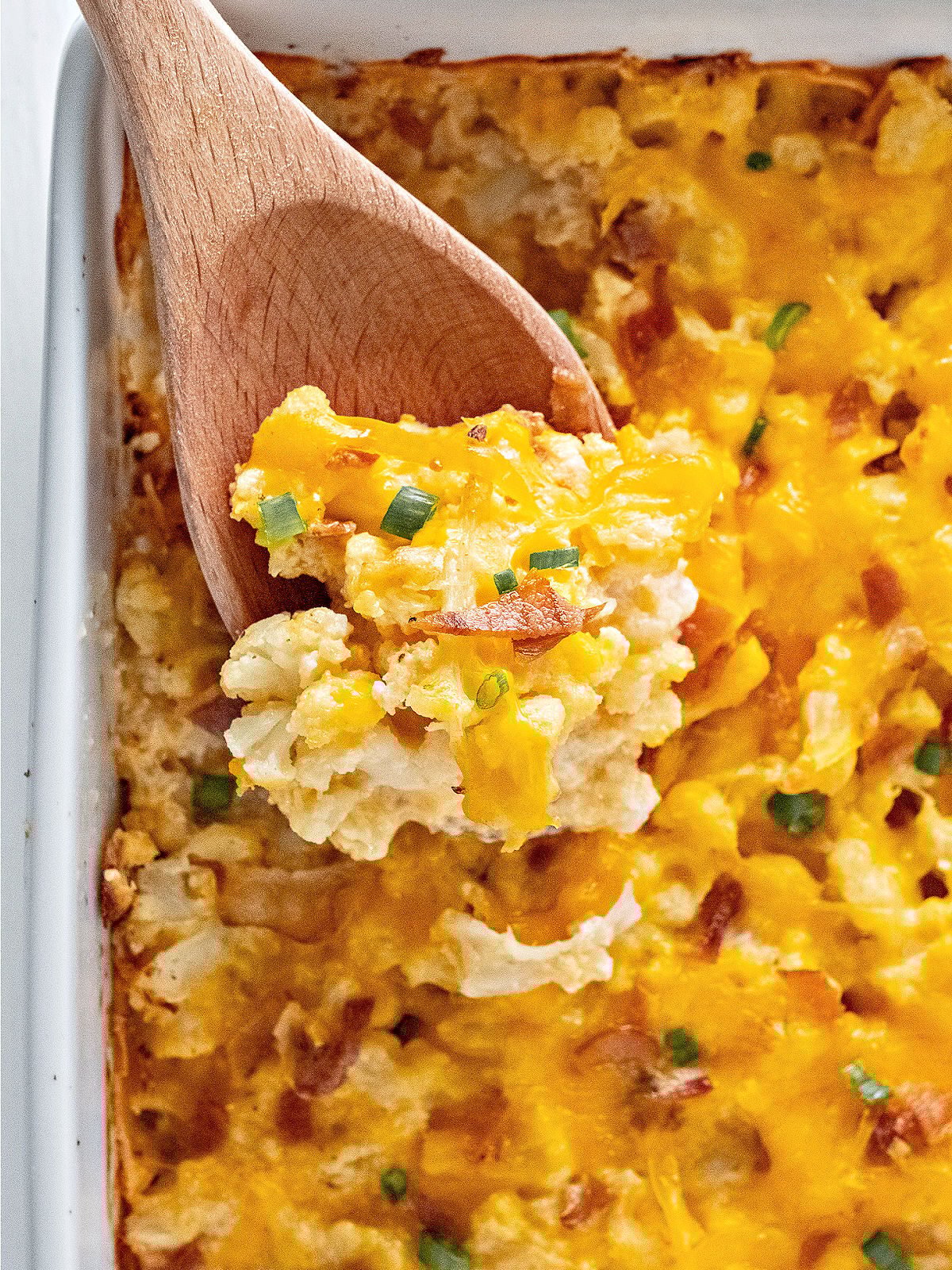 Wooden spoon with serving of cauliflower casserole.