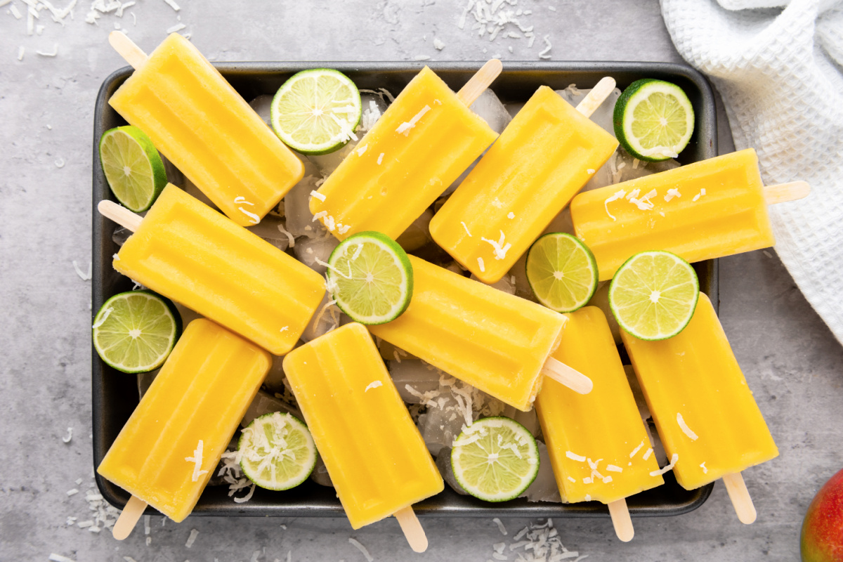 Pan of ice topped with mango popsicles.