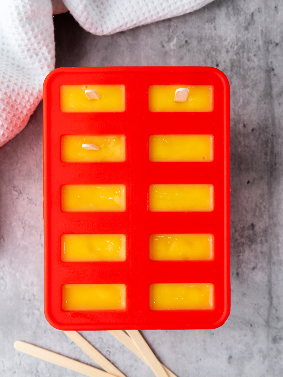 Mango popsicle filling in a popsicle mold.