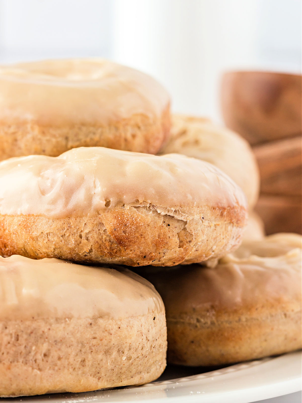 White plate stacked with glazed maple doughnuts.
