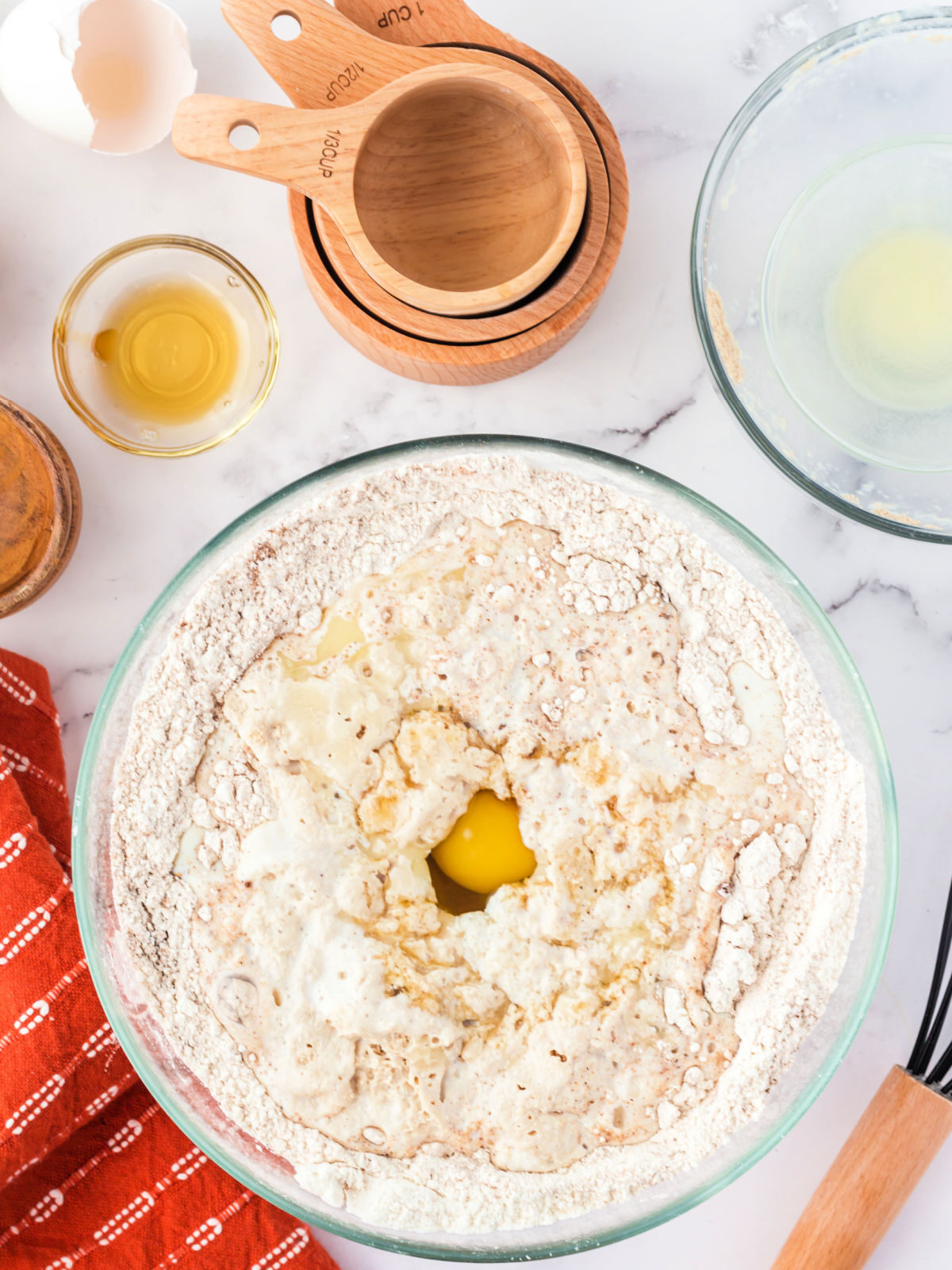 Glass bowl with flour and cracked egg.