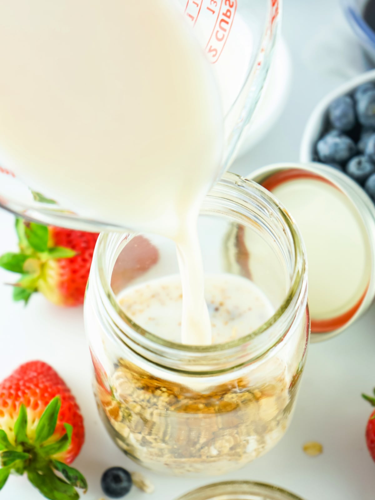 Milk being poured into a glass with oats.