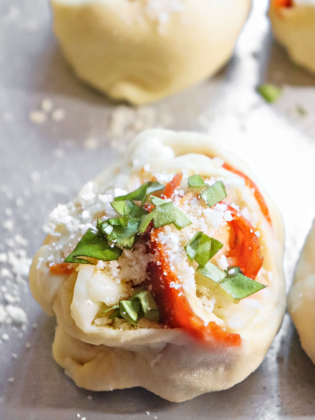 Unbaked pizza bite topped with fresh basil.