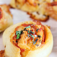Pepperoni pizza bite topped with basil.