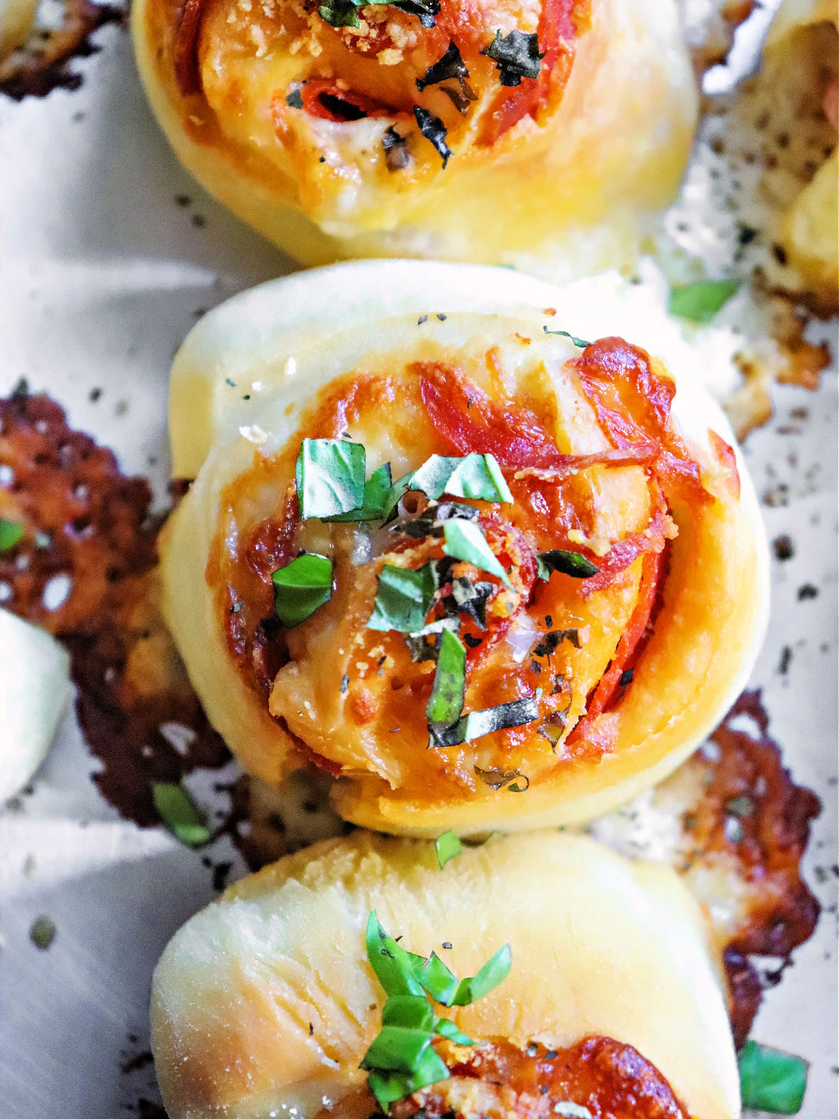Baked pizza pinwheels on a metal baking sheet.