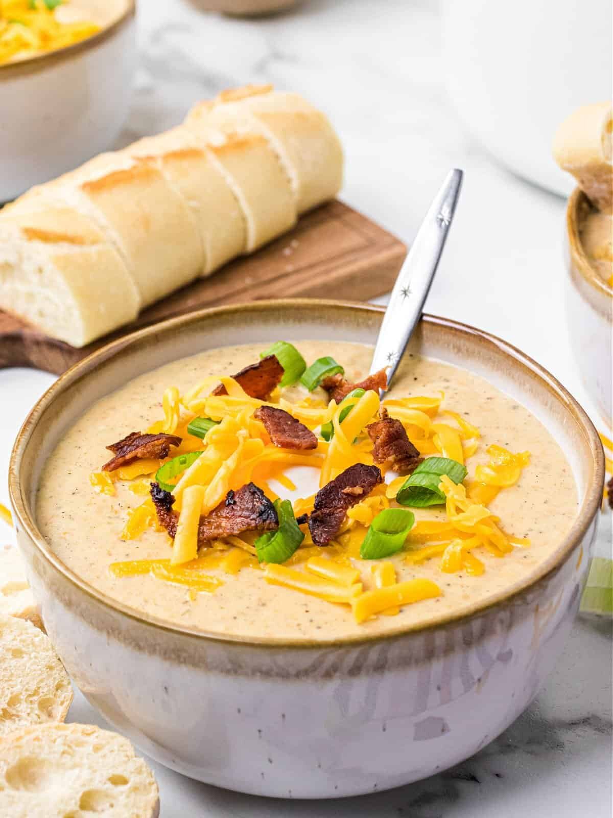 Potato Soup Bowl of potato soup topped with bacon, cheese, and chives with loaf of bread.