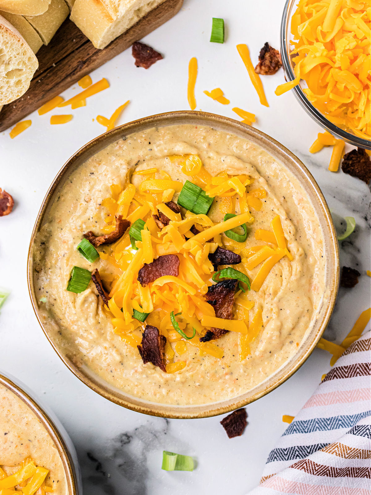 Potato Soup Bowl of potato soup topped with bacon, cheese, and chives with loaf of bread.