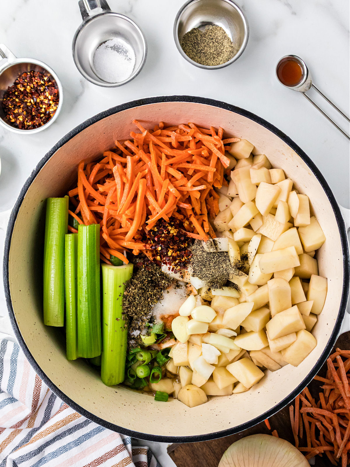 Pot filled with carrots, potatoes, celery, and spices.