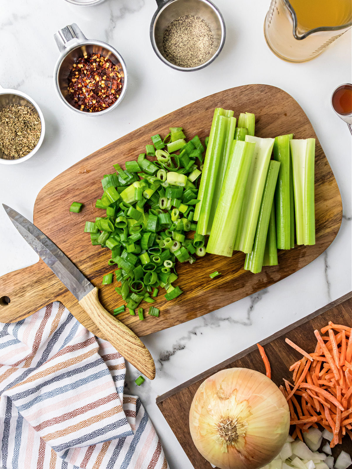 Celery and chives chopped on a cutting board.