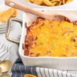 White casserole dish filled with sloppy Joe dip and corn chips on the side.