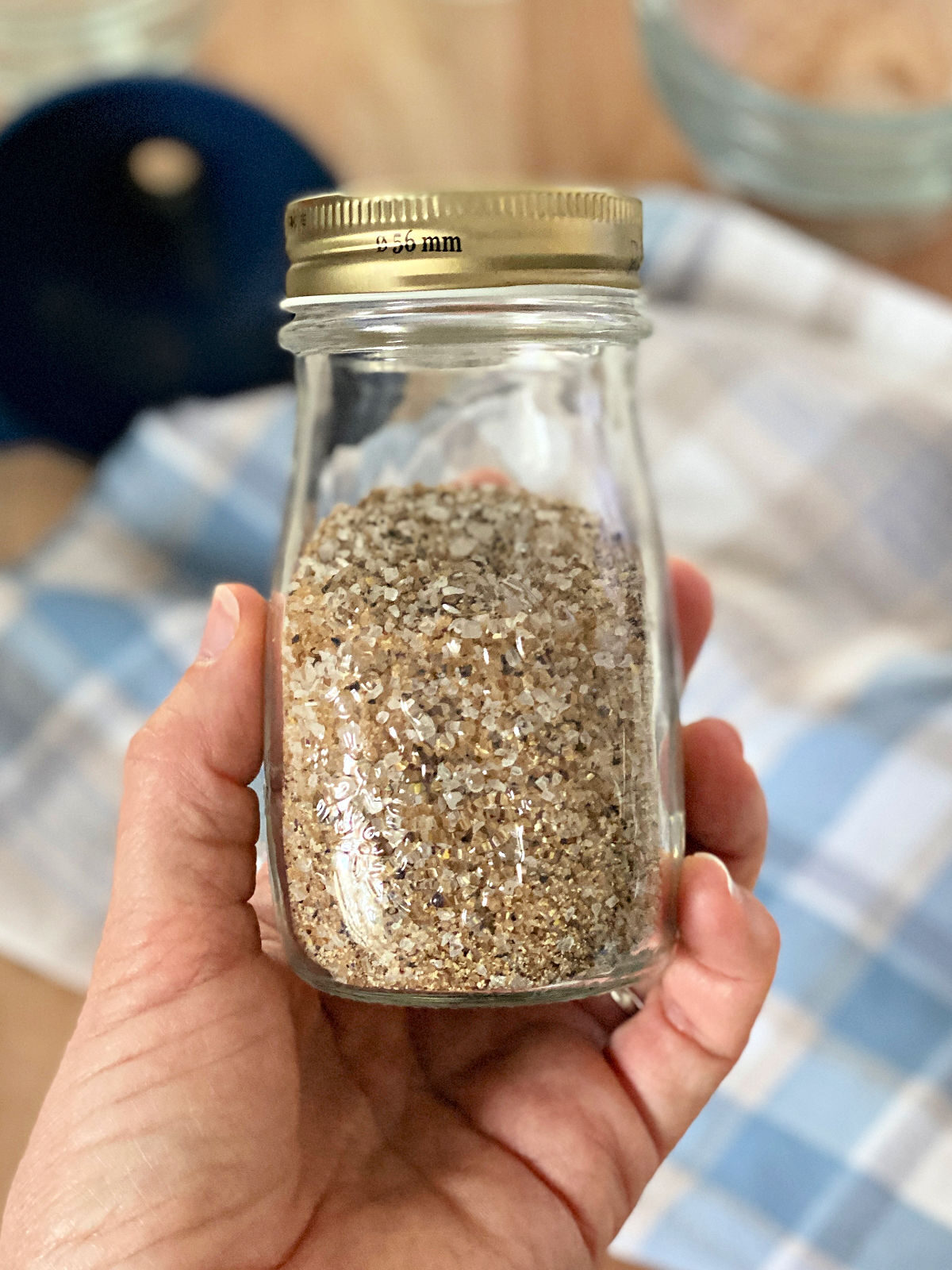 Hand holding a glass bottle with spices.