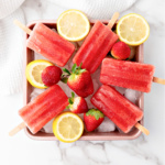 Strawberry popsicles on top of ice cubes.