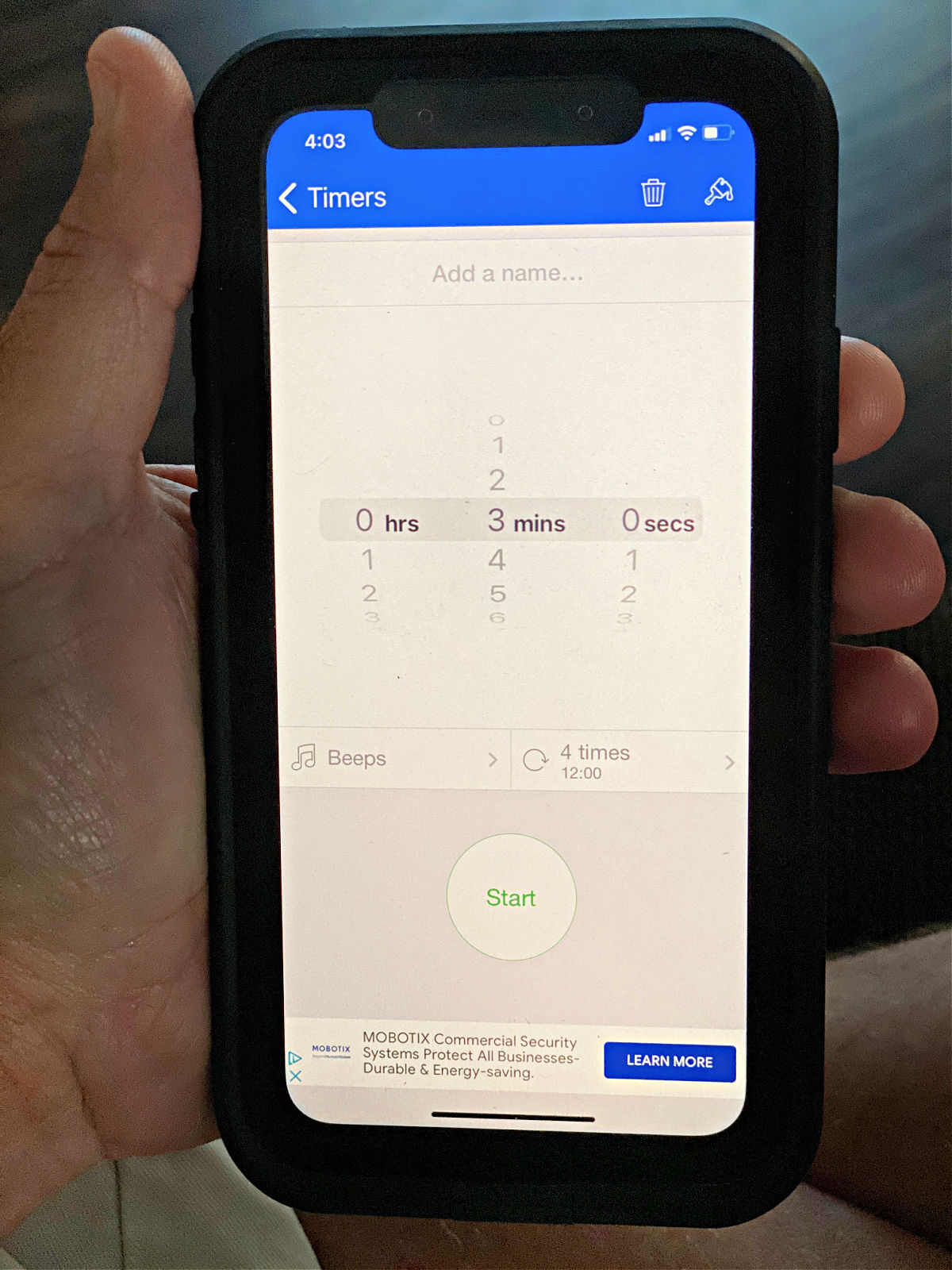 Hand holding an iPhone with a timer app on the screen.