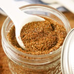 White spoon in a jar of chili seasoning.