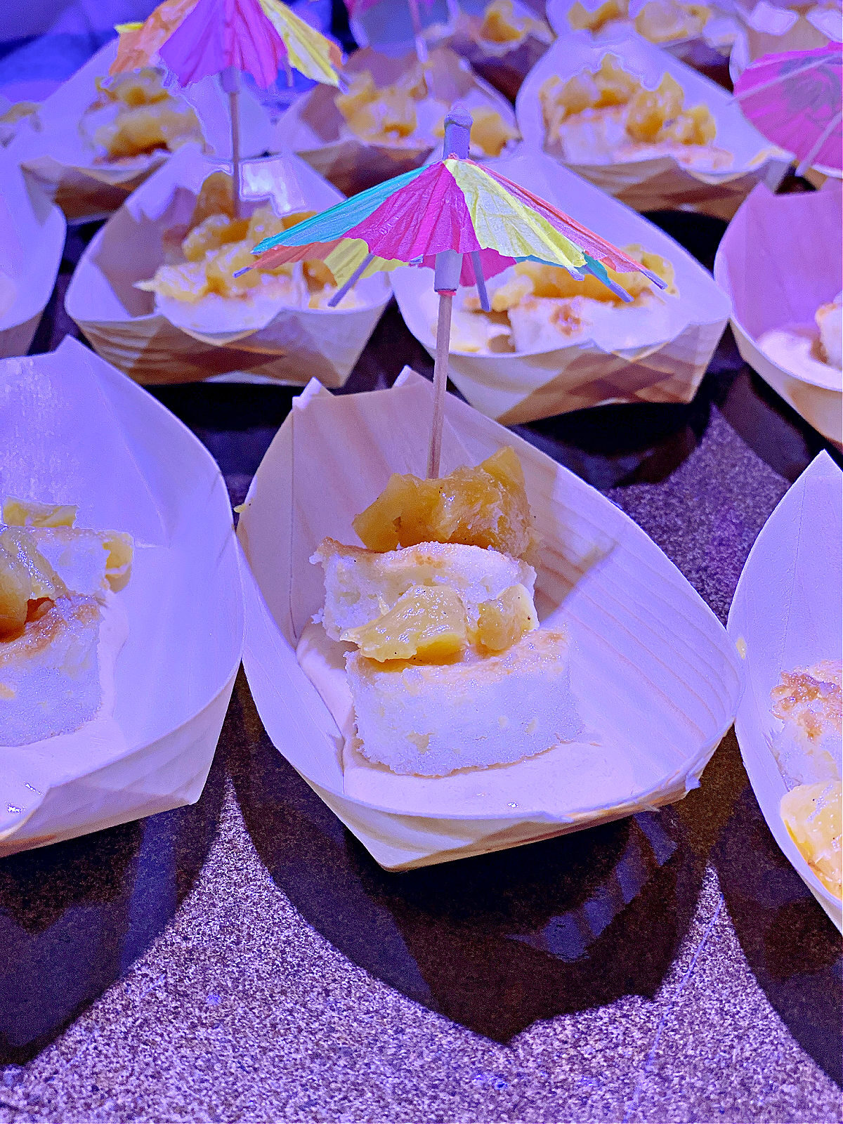 Sweet tropical dessert in a boat shaped bowl with a colorful umbrella.