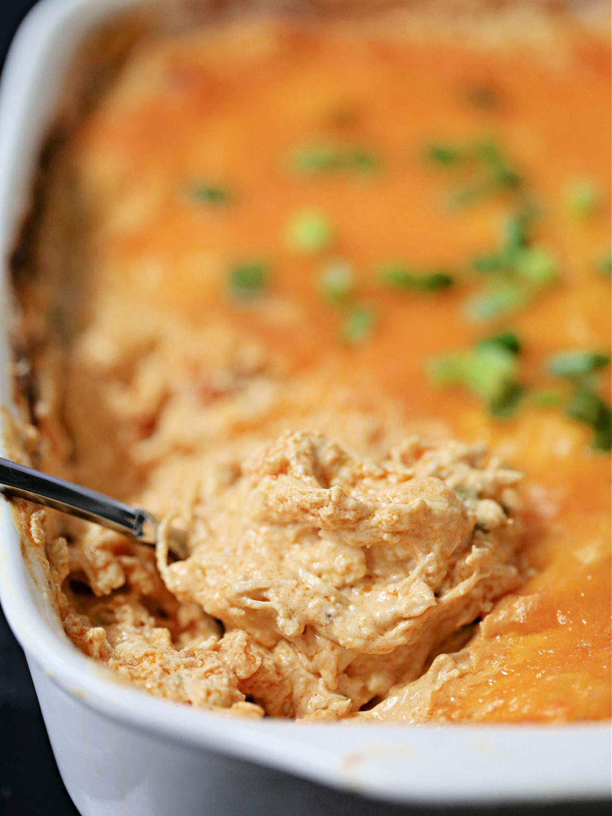 Buffalo dip in a white casserole dish.