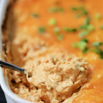 Buffalo dip in a white casserole dish.