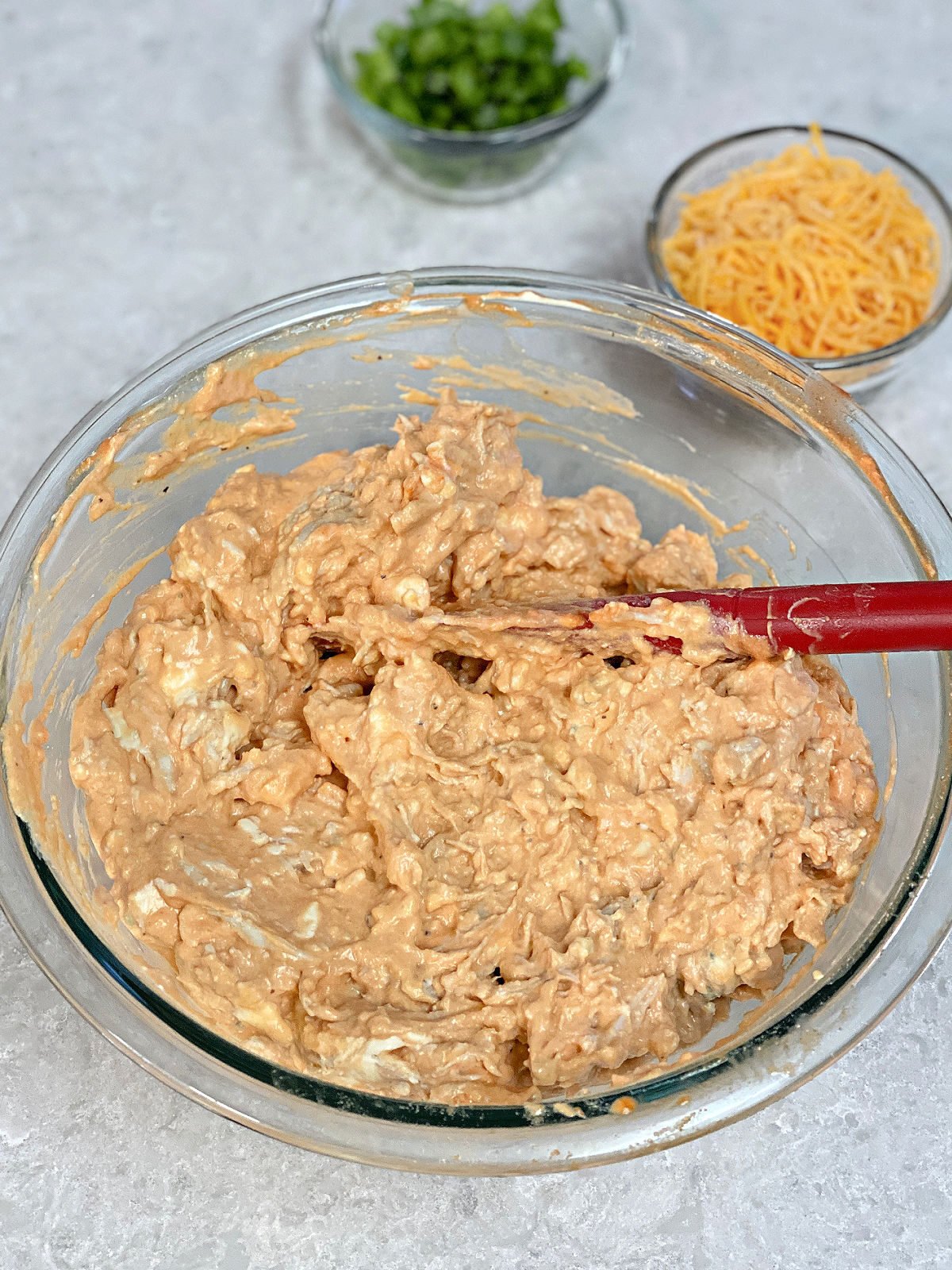 Buffalo chicken dip being mixed in a glass bowl.