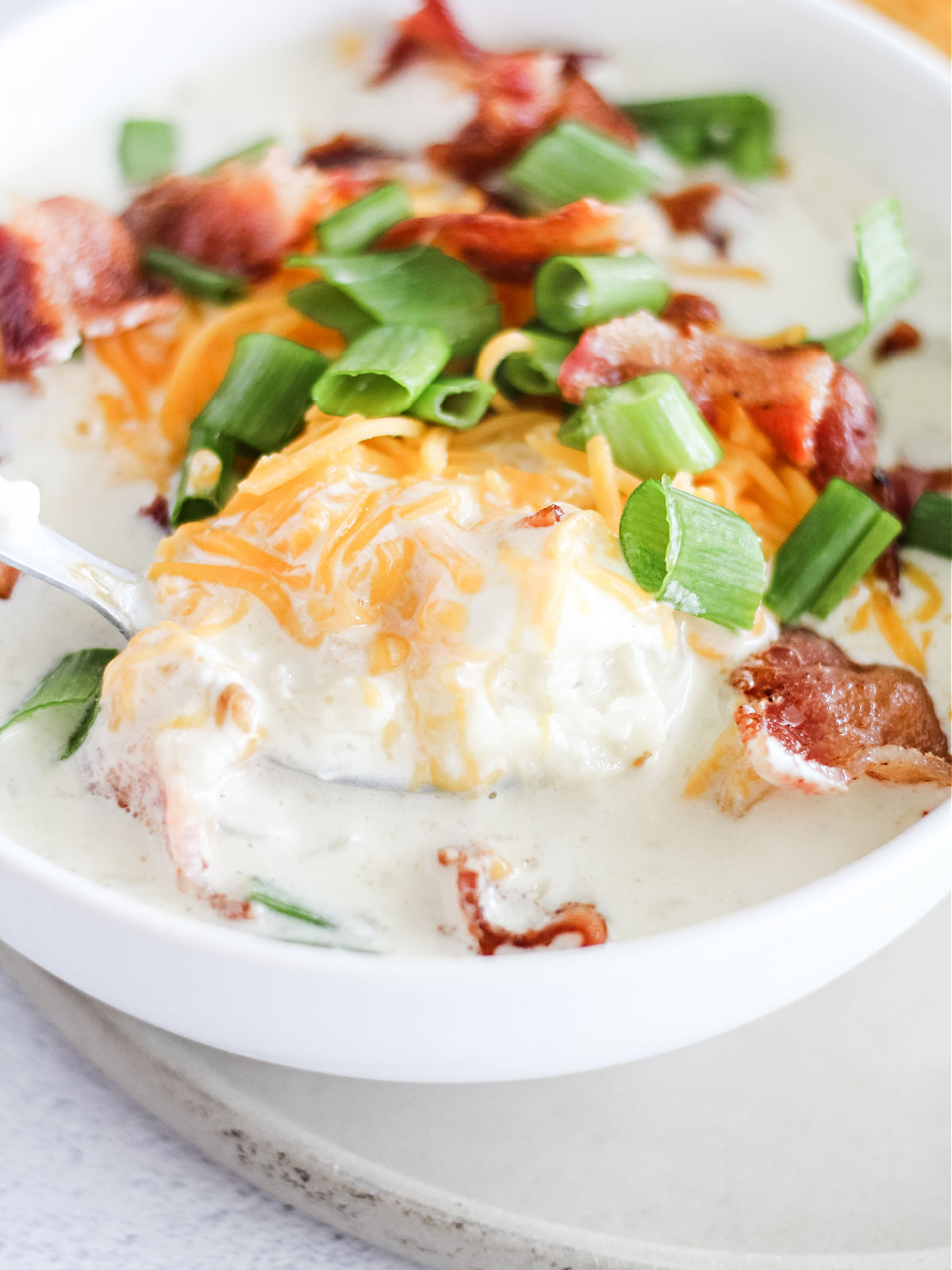 A spoonful of cauliflower soup topped with Cheddar cheese.
