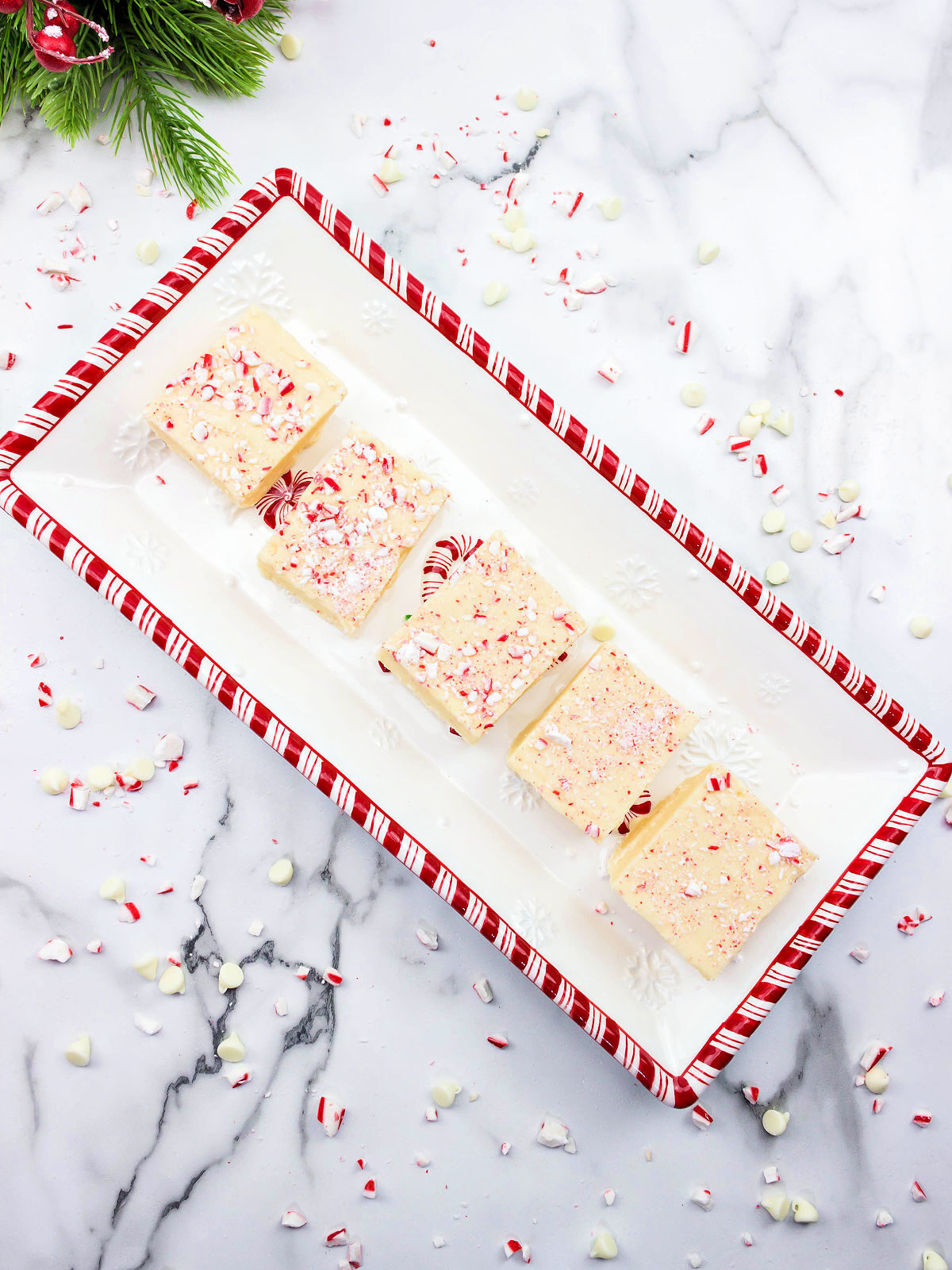 Peppermint white chocolate fudge on a red and white striped plate.