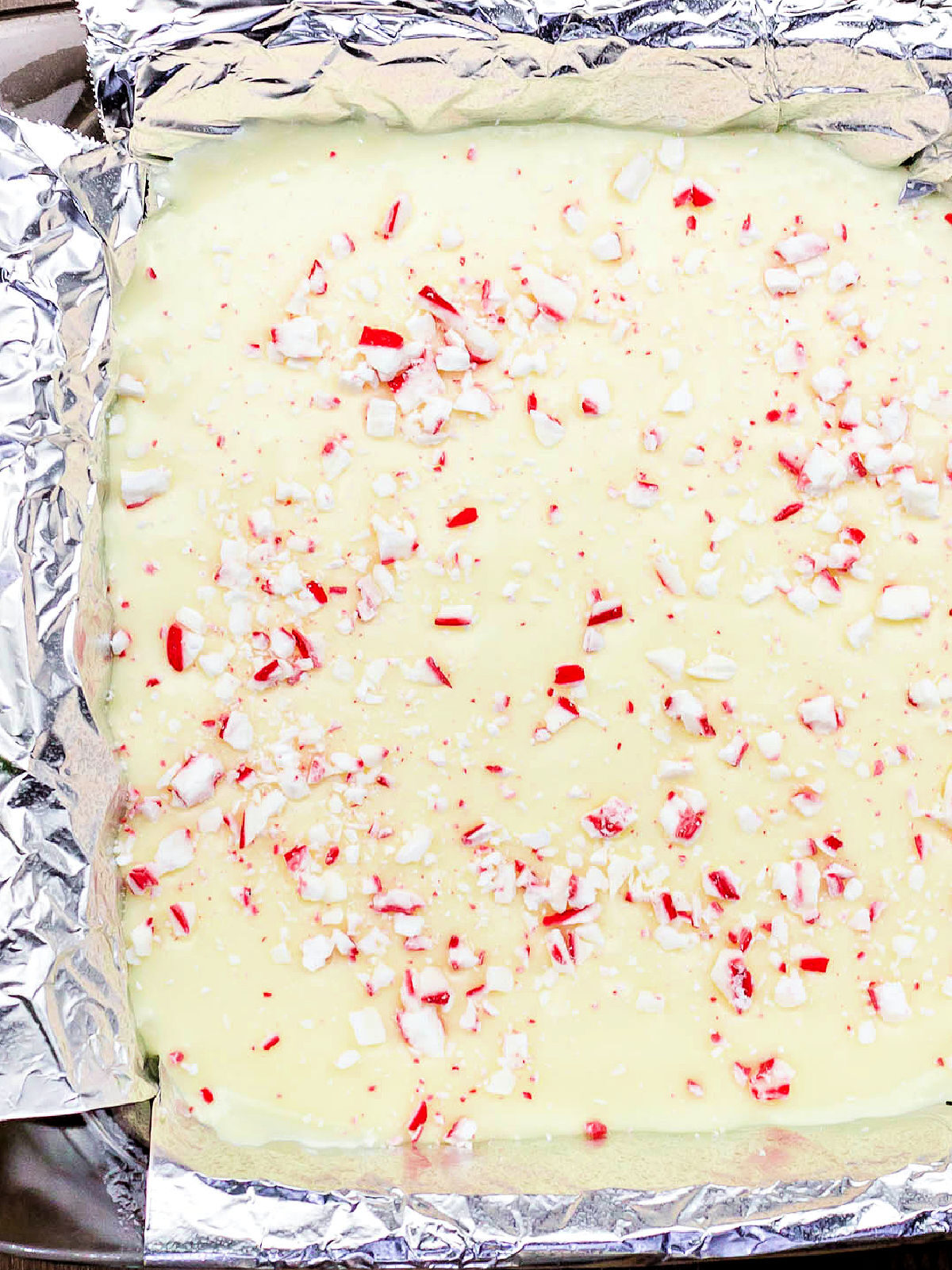 White chocolate fudge topped with peppermint in a foil-lined pan.