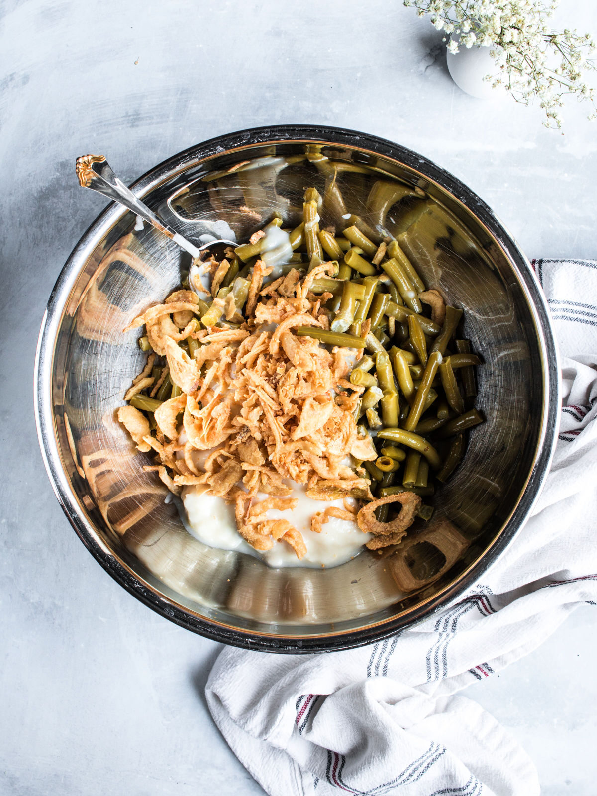 Green beans, soup, and fried onions in a metal mixing bowl.
