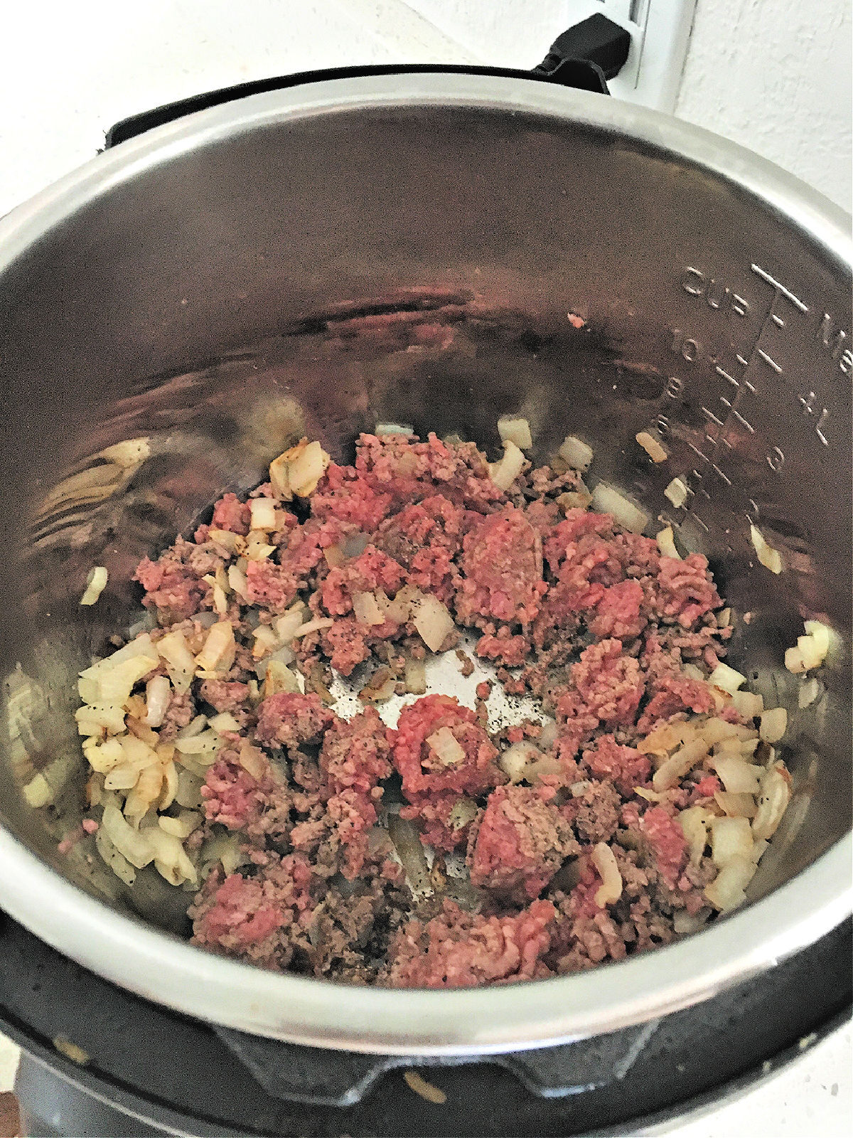 Ground beef and onions cooking in an Instant Pot.