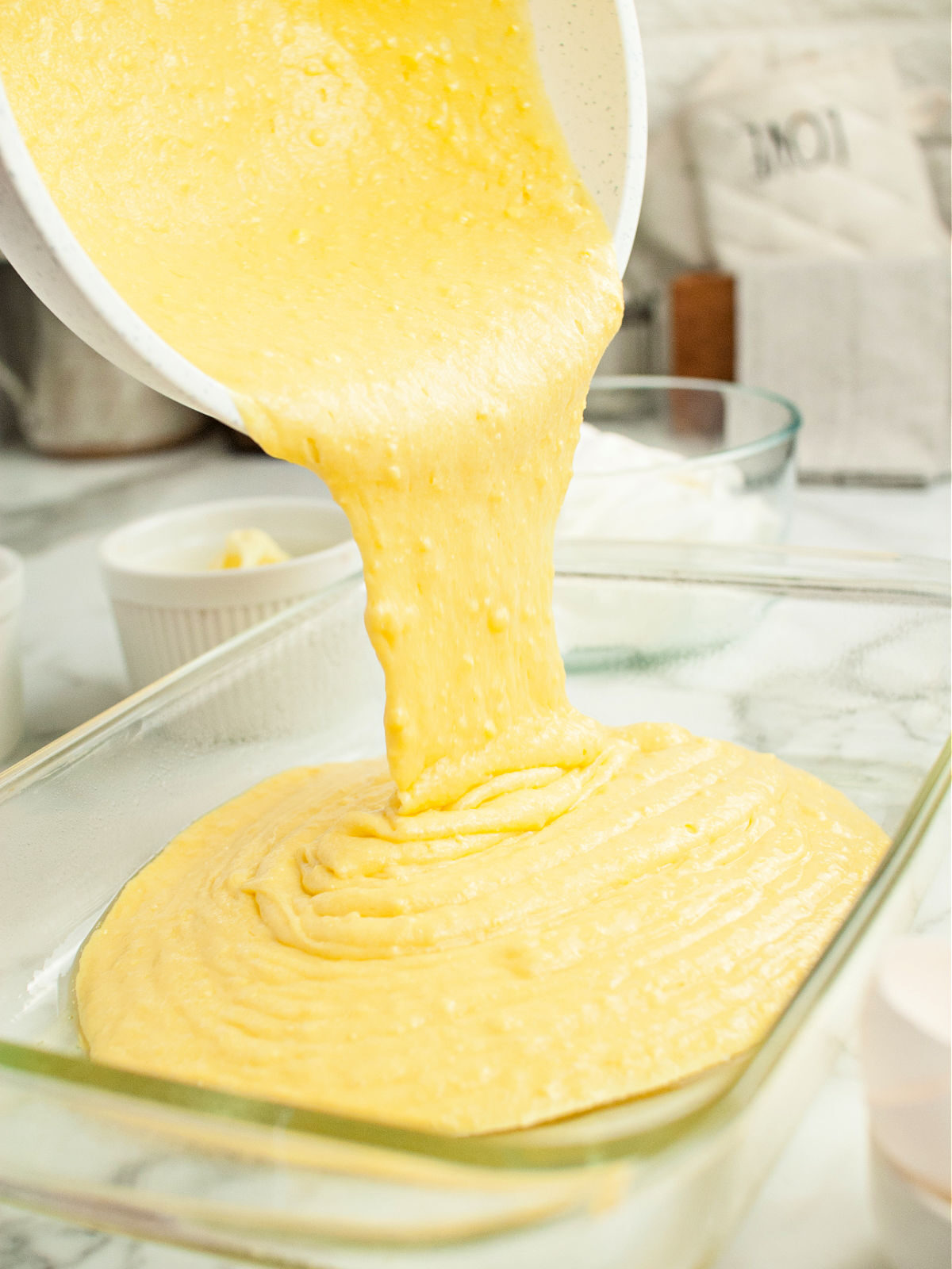 Pouring lemon cake batter into a baking pan.