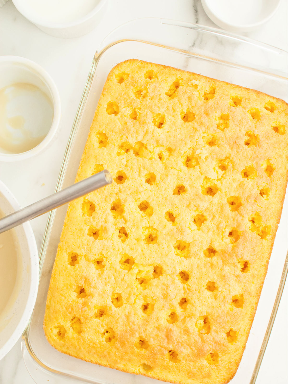 Punching holes in a cake with a straw.