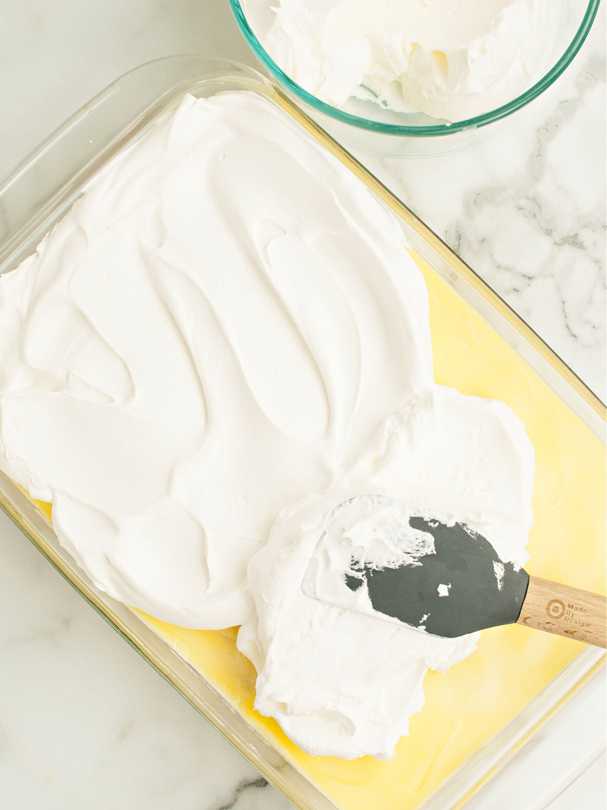 Spatula spreading whipped topping on pudding layer.