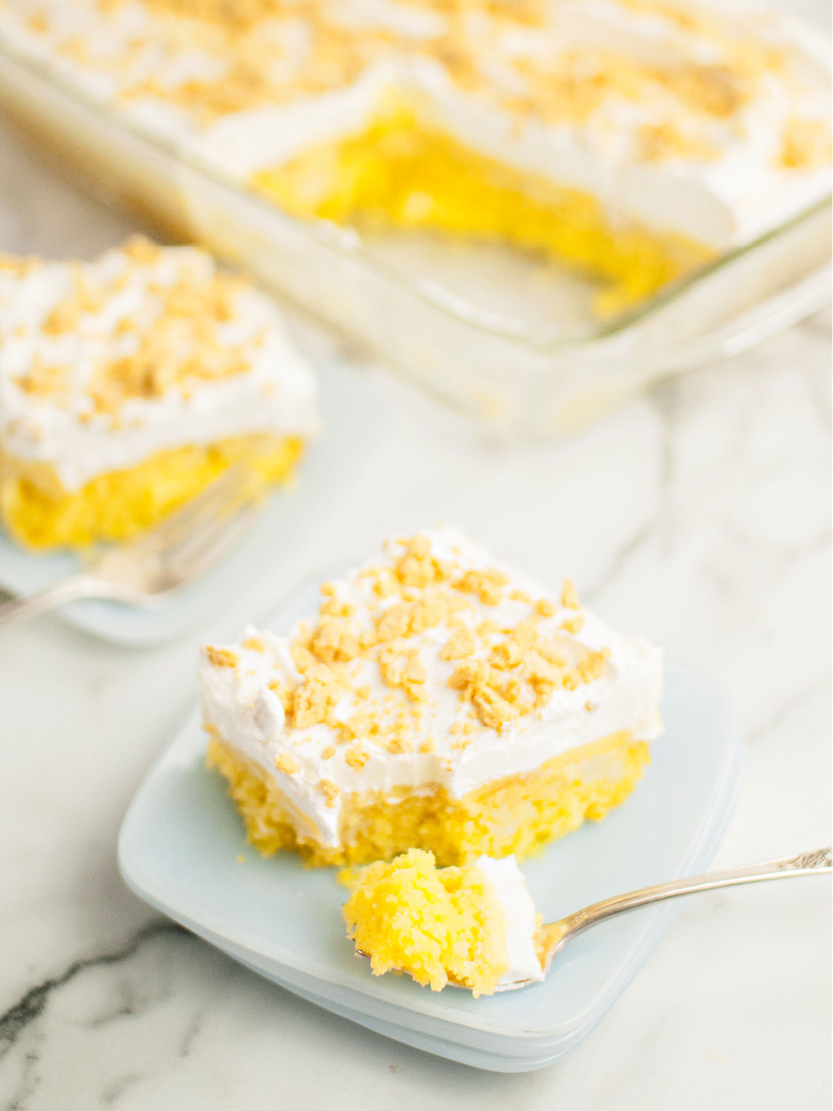 Slice of lemon poke cake topped with crushed cookies on a plate with a fork.