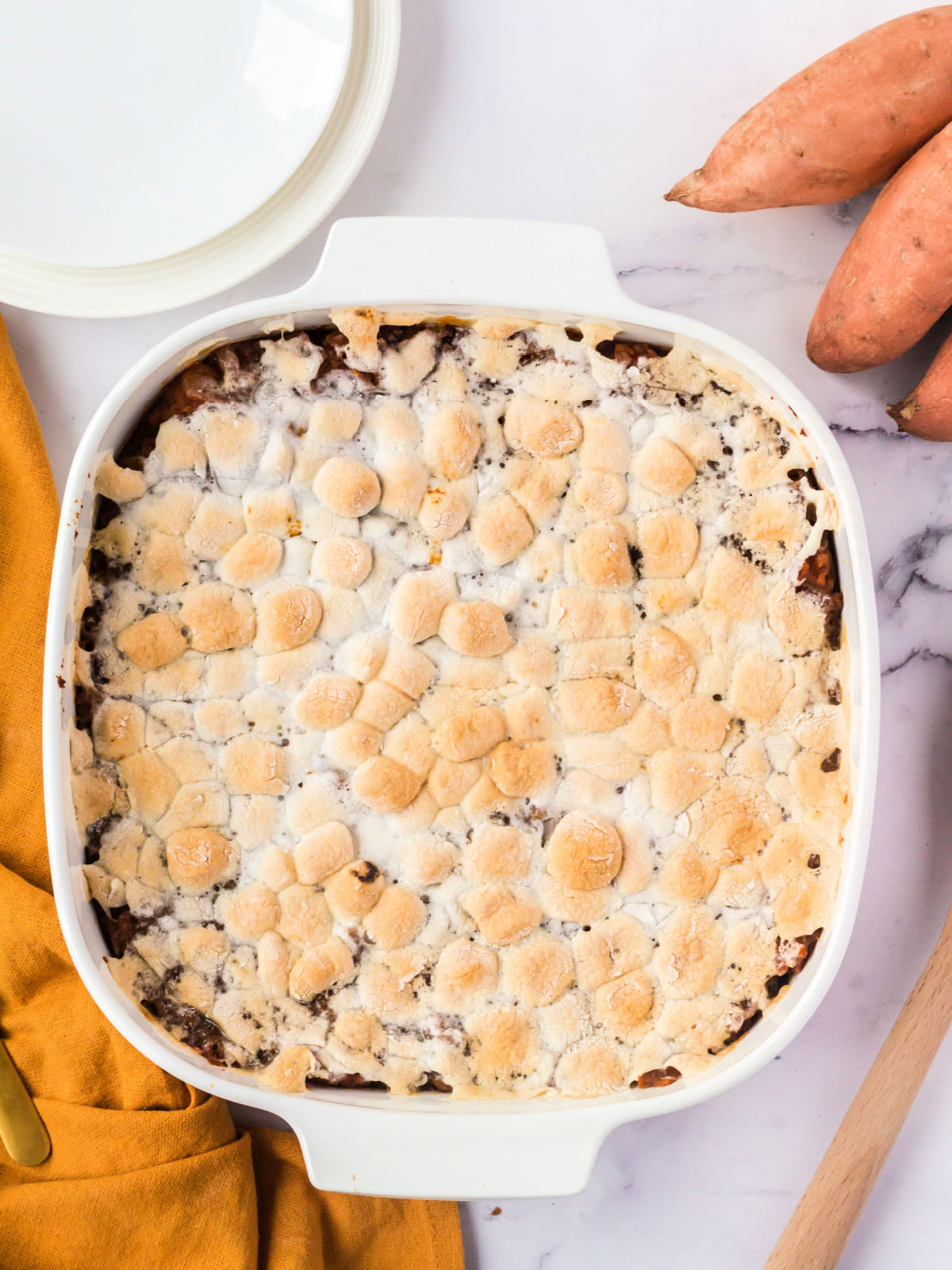 Sweet potato casserole toped with toasted marshmallows in a white baking dish.
