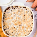 Sweet potato casserole toped with toasted marshmallows in a white baking dish.
