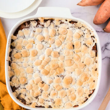Sweet potato casserole toped with toasted marshmallows in a white baking dish.