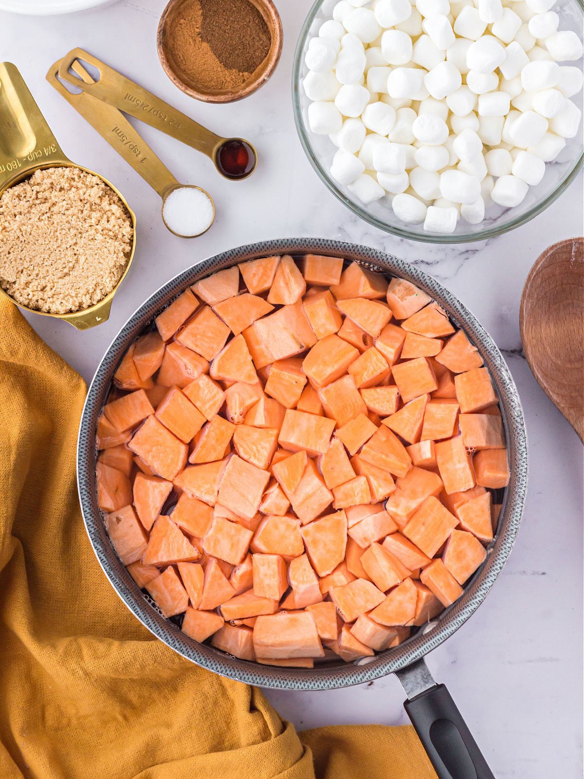 Sweet potatoes in a pot and marshmallows in a glass bowl.