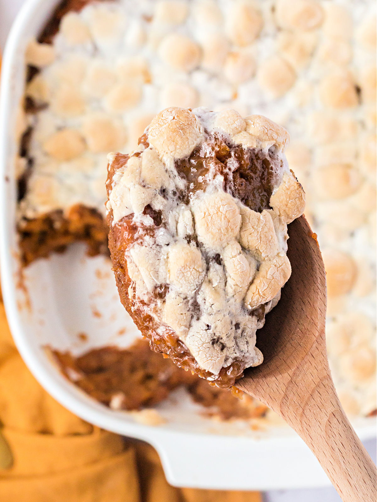 Wooden spoon with sweet potatoes and melted marshmallows.