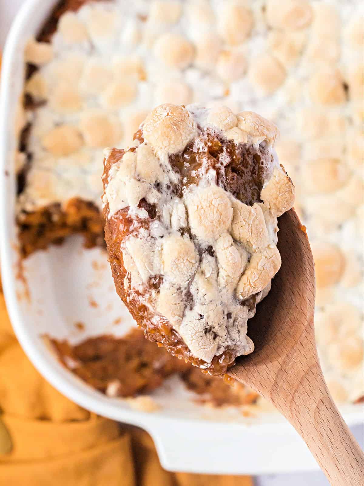 Wooden spoon with sweet potatoes and melted marshmallows.