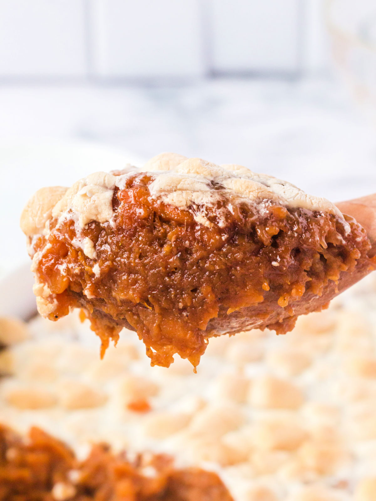 Wooden spoon with a scoop of sweet potato casserole.